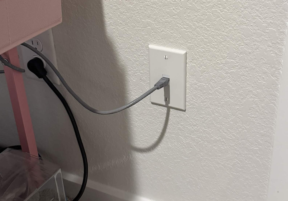 Ethernet cable plugged into a wallplate beside a desk