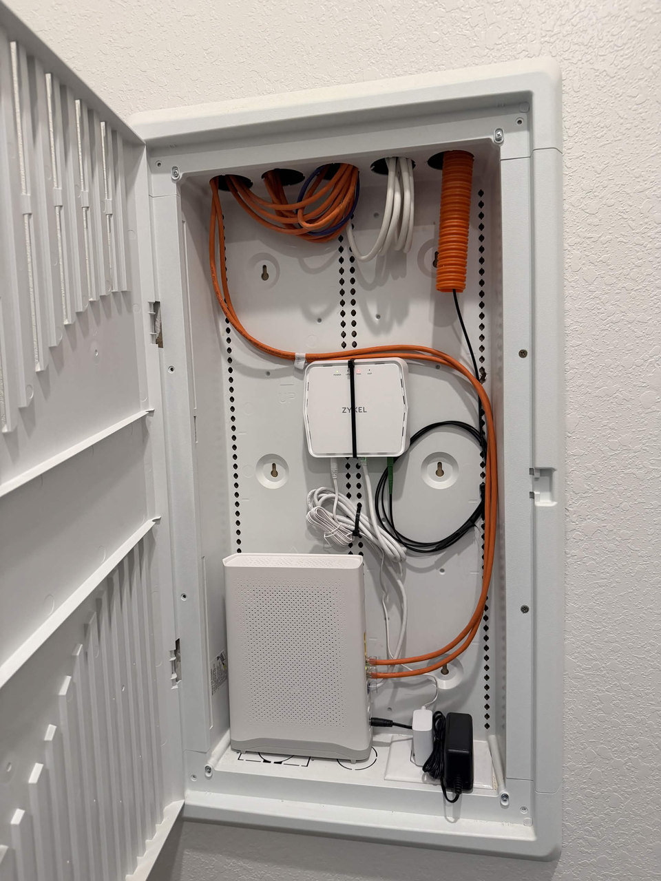 White network enclosure with orange cabling and organized equipment