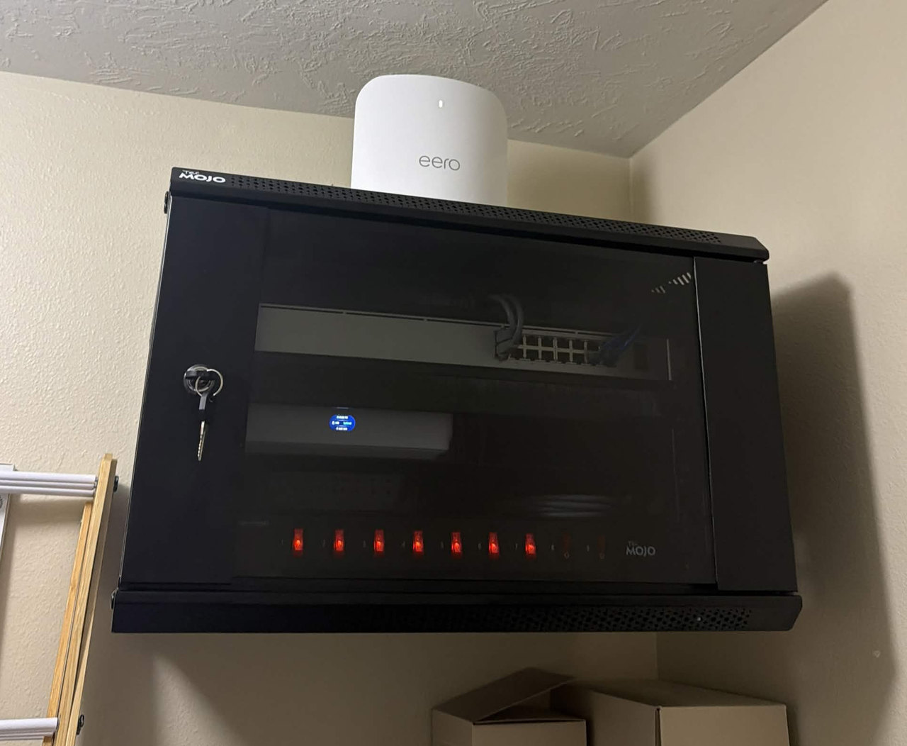 Black wall-mounted network rack with an eero router above it