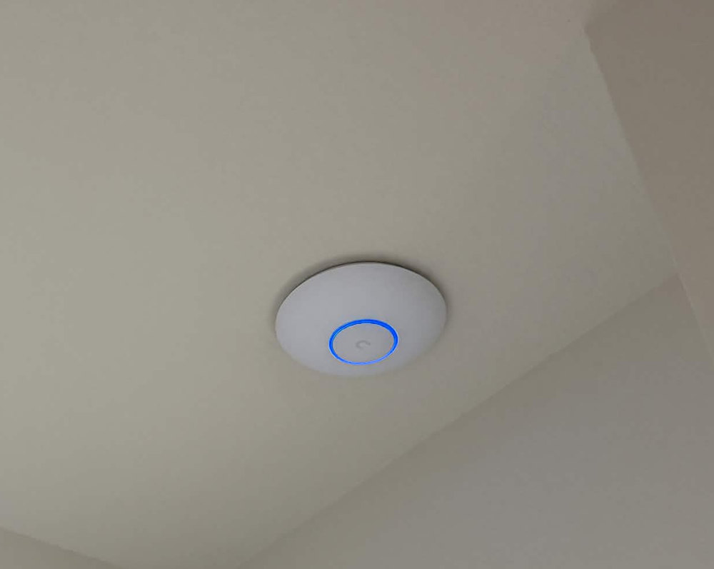 Ceiling-mounted Wi-Fi access point with a blue status ring